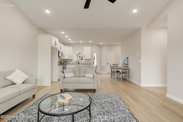 living room with visible vents, baseboards, a ceiling fan, light wood-style flooring, and recessed lighting