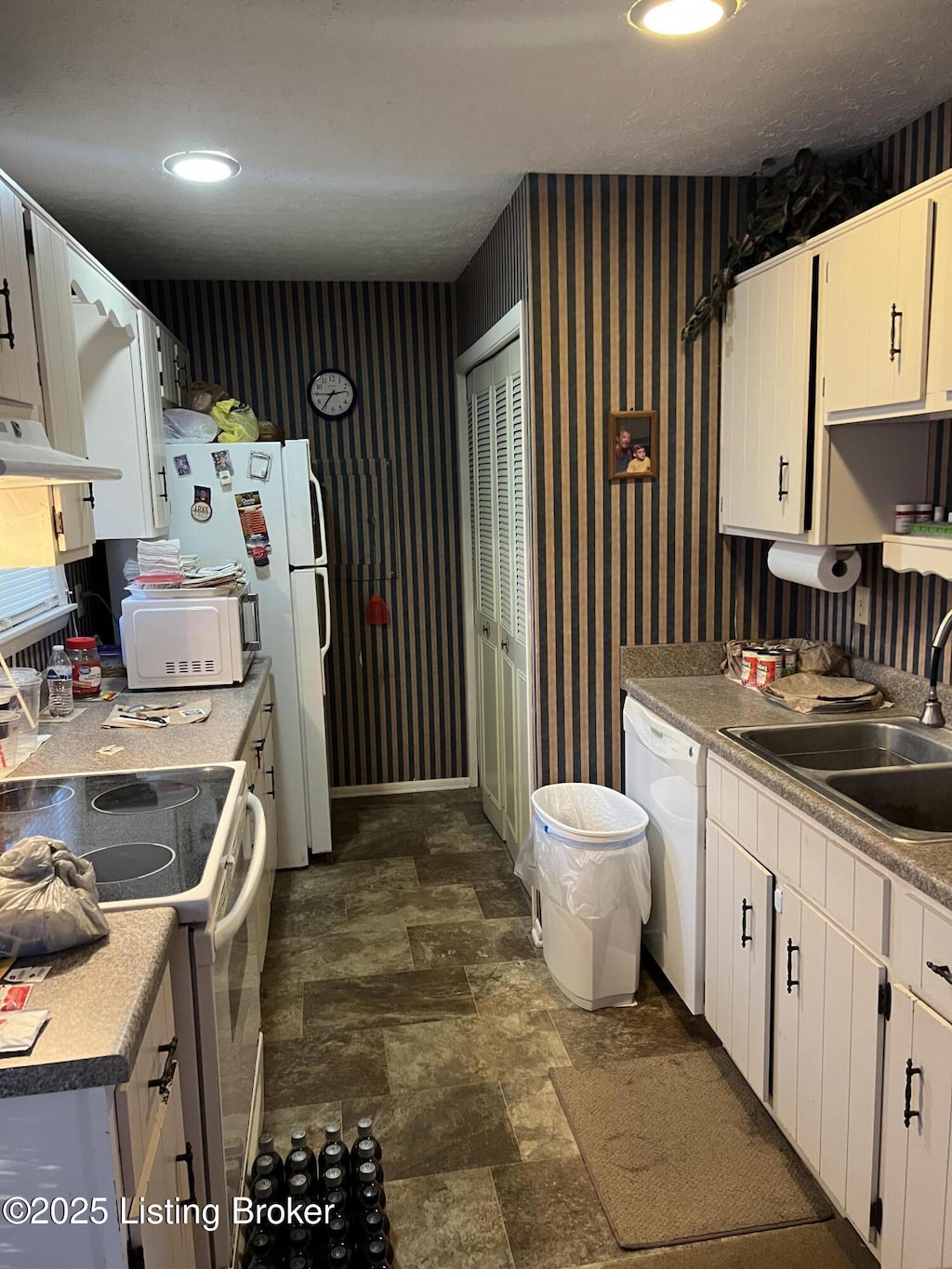 kitchen featuring white cabinetry, sink, and white appliances