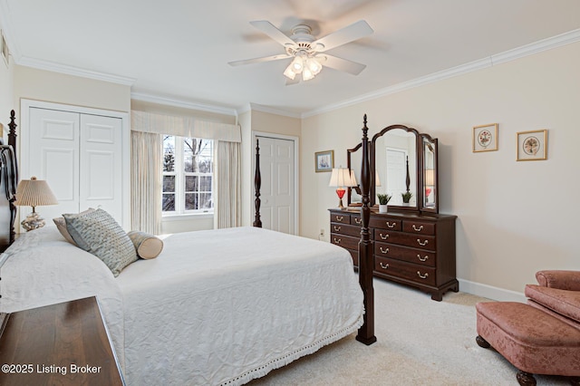 bedroom featuring crown molding, light colored carpet, ceiling fan, and two closets