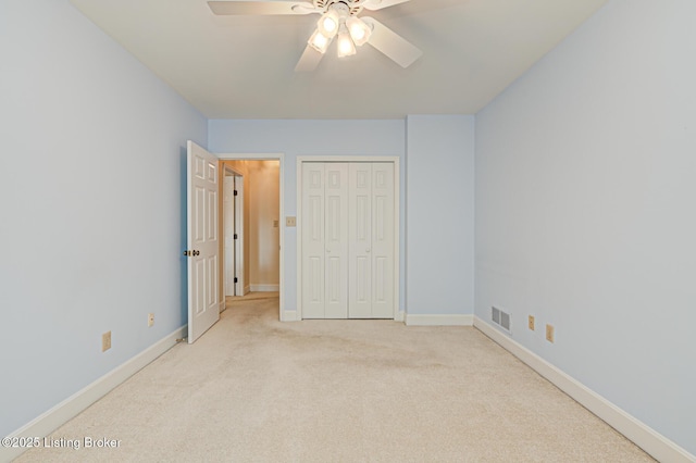 unfurnished bedroom with light colored carpet, ceiling fan, and a closet