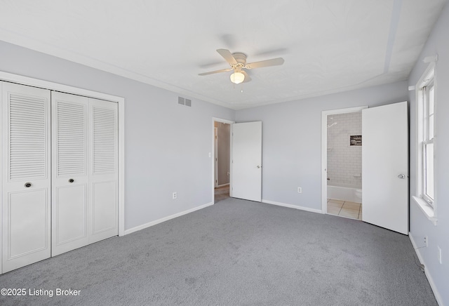 unfurnished bedroom featuring ensuite bathroom, light colored carpet, ceiling fan, and a closet