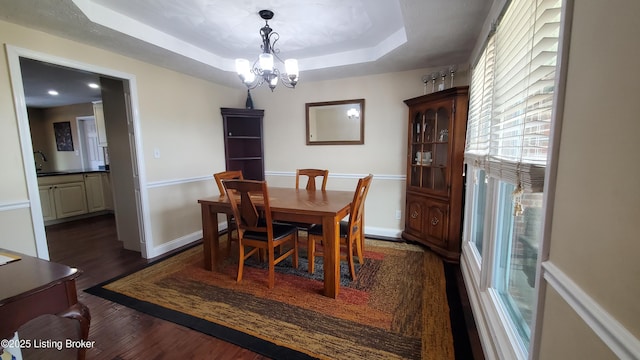 dining space featuring an inviting chandelier, dark hardwood / wood-style floors, a raised ceiling, and sink