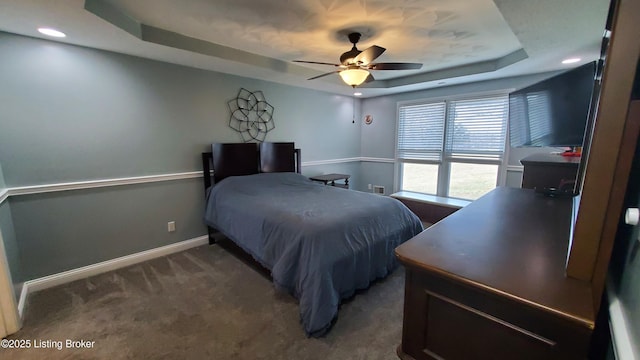 carpeted bedroom featuring a raised ceiling and ceiling fan