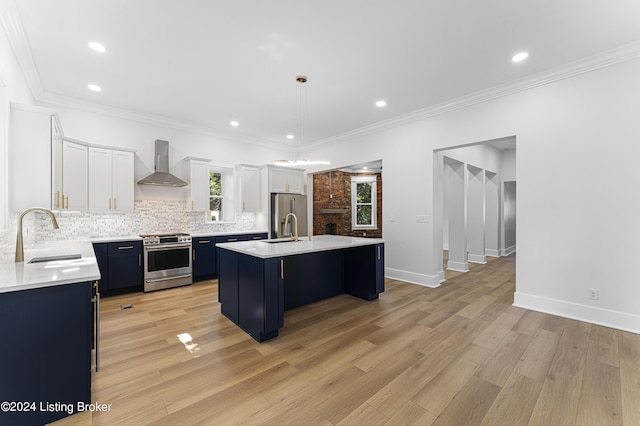 kitchen featuring wall chimney exhaust hood, sink, hanging light fixtures, a kitchen island, and stainless steel appliances