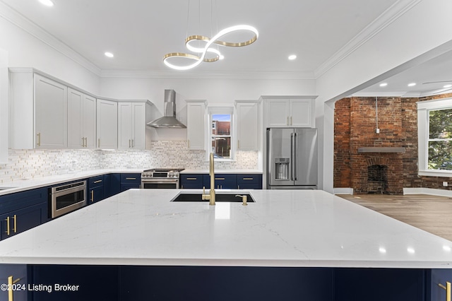 kitchen with wall chimney exhaust hood, sink, high end appliances, pendant lighting, and a large island