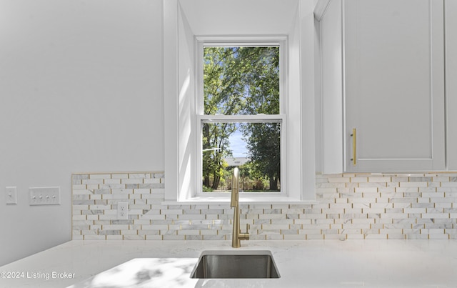 details with light stone counters, white cabinetry, and sink