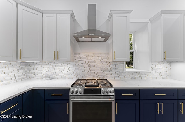 kitchen with blue cabinets, stainless steel gas stove, tasteful backsplash, wall chimney range hood, and white cabinets