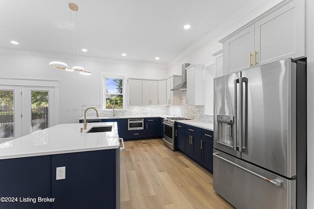 kitchen featuring blue cabinetry, hanging light fixtures, stainless steel appliances, white cabinets, and wall chimney exhaust hood