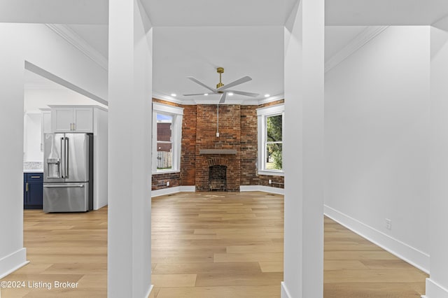 unfurnished living room featuring brick wall, a brick fireplace, and light wood-type flooring