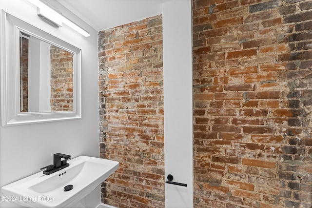 bathroom with sink and brick wall