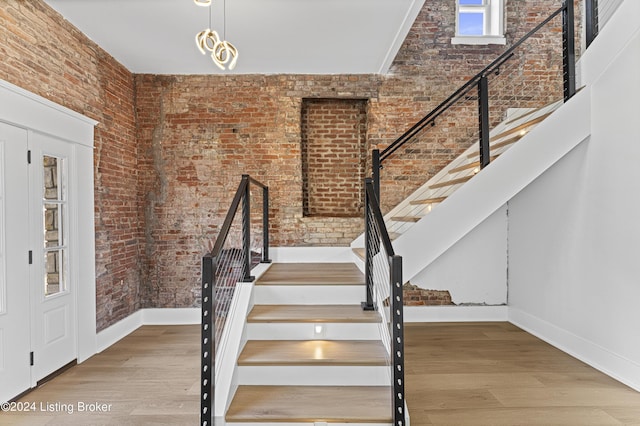 stairway featuring hardwood / wood-style flooring and brick wall