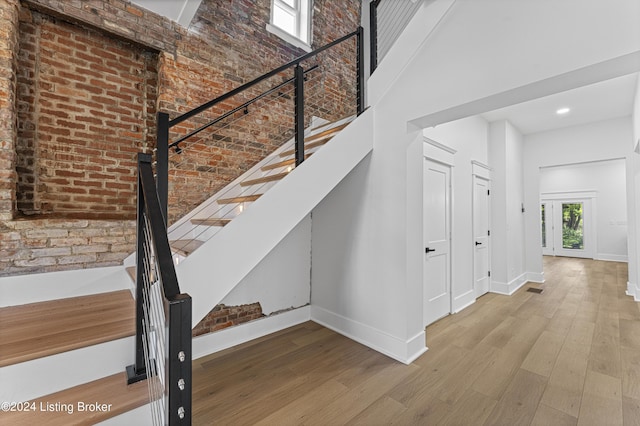 staircase featuring wood-type flooring and a high ceiling