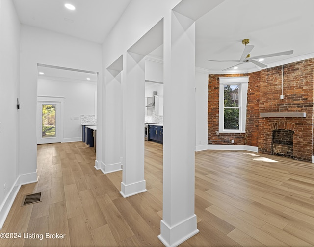 interior space featuring ceiling fan, a brick fireplace, and light hardwood / wood-style floors