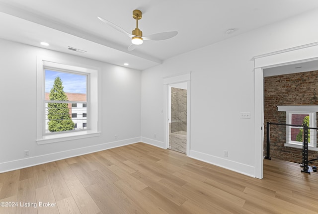 unfurnished room with a fireplace, ceiling fan, and light wood-type flooring