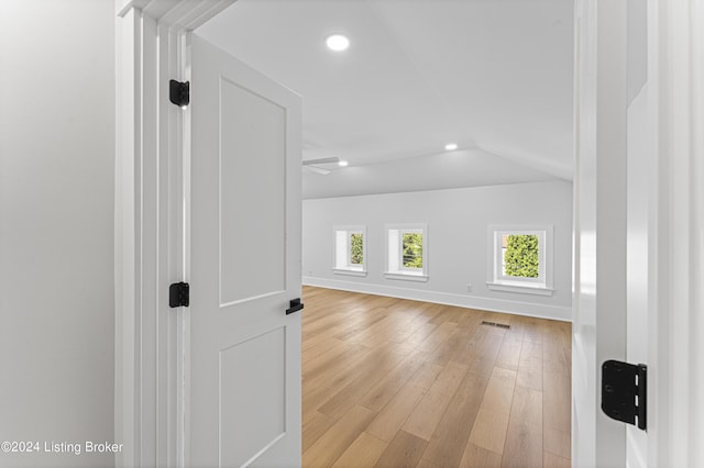 additional living space featuring vaulted ceiling and light hardwood / wood-style floors