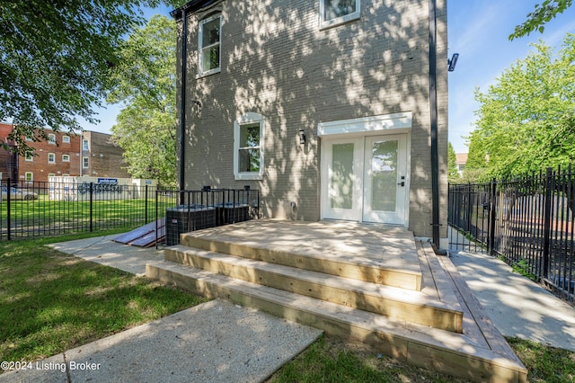 doorway to property with a lawn, french doors, central air condition unit, and a deck