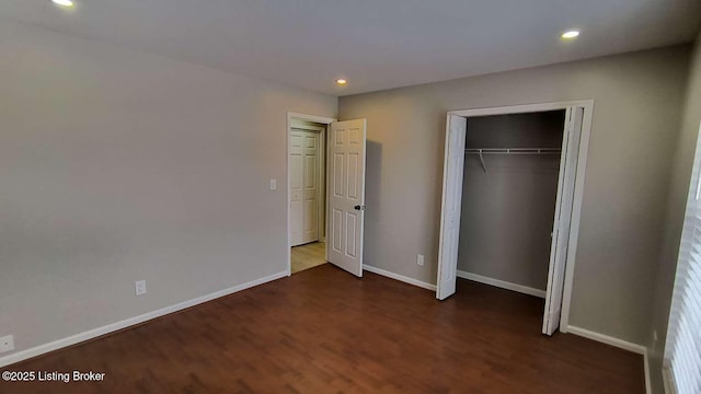 unfurnished bedroom featuring dark hardwood / wood-style flooring and a closet