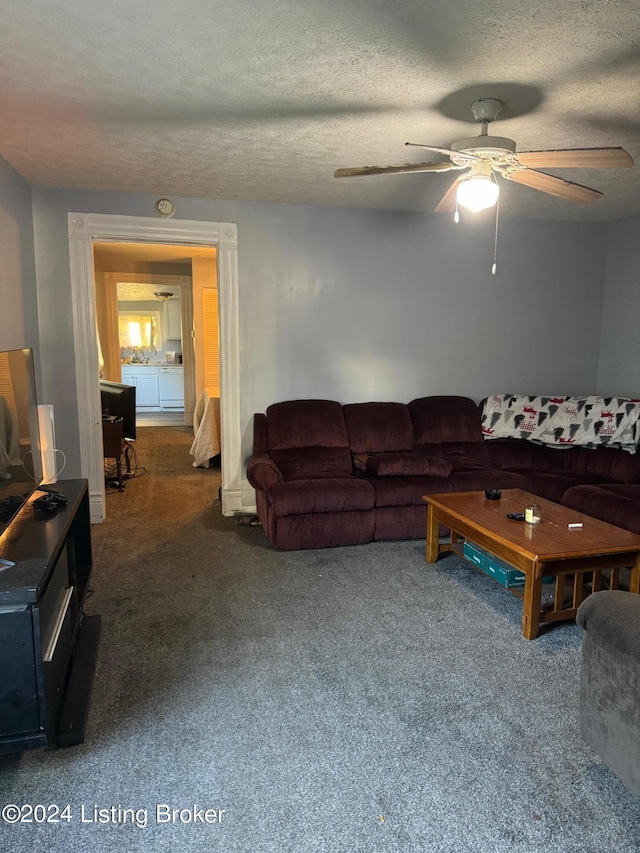 living room with ceiling fan, dark carpet, and a textured ceiling