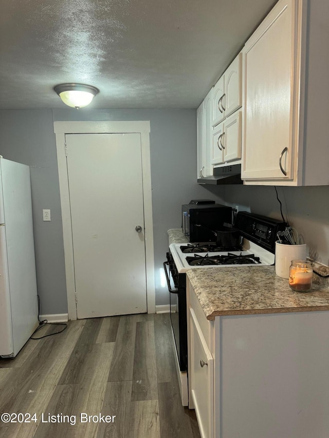 kitchen with black gas range, a textured ceiling, white cabinets, dark hardwood / wood-style flooring, and white fridge