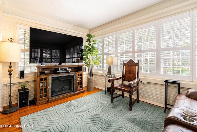 living area with brick wall, hardwood / wood-style floors, and a tile fireplace