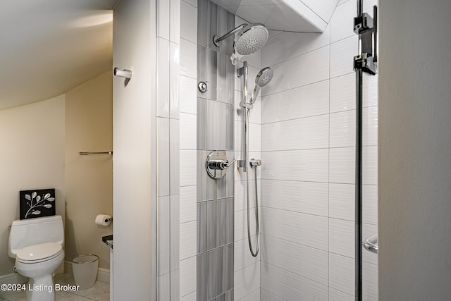 bathroom featuring tiled shower, toilet, and tile patterned flooring