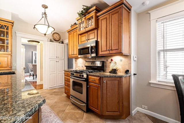 kitchen featuring sink, appliances with stainless steel finishes, tasteful backsplash, decorative light fixtures, and dark stone counters