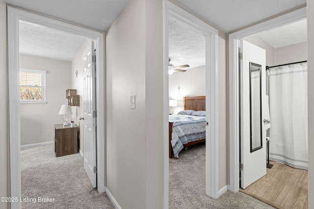 hall with light carpet and a textured ceiling