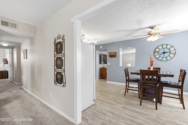 dining space featuring ceiling fan, light hardwood / wood-style floors, and a textured ceiling