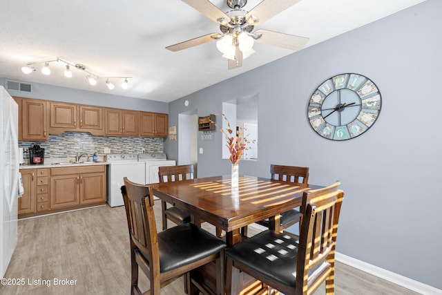 dining space featuring ceiling fan, sink, washer and clothes dryer, and light hardwood / wood-style floors