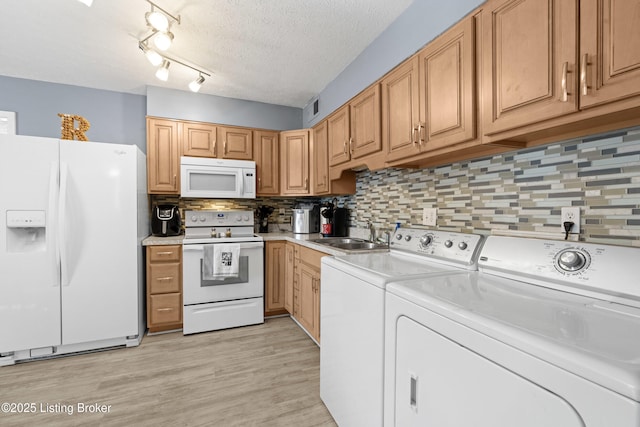 kitchen featuring sink, washer and dryer, a textured ceiling, white appliances, and backsplash