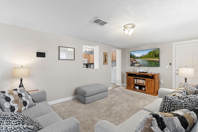 carpeted living room with washer / clothes dryer and a textured ceiling