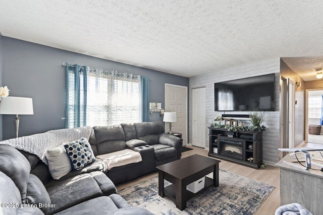 living room with plenty of natural light, a textured ceiling, and light hardwood / wood-style flooring