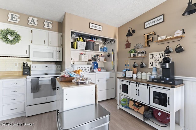 kitchen with white appliances, light hardwood / wood-style flooring, white cabinetry, washing machine and dryer, and a textured ceiling