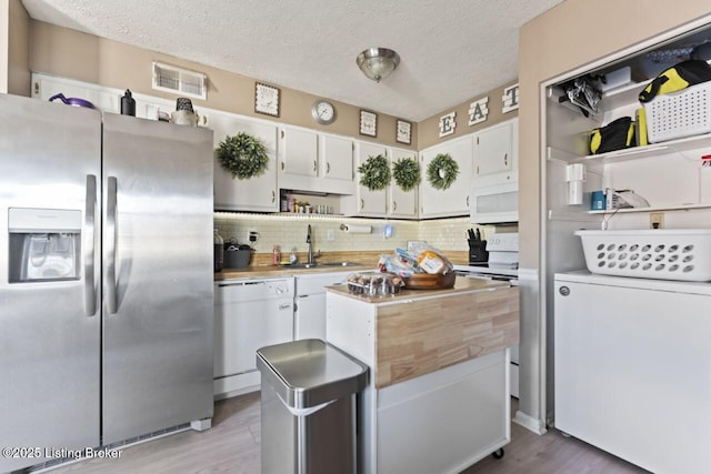 kitchen featuring sink, white appliances, white cabinetry, decorative backsplash, and light wood-type flooring