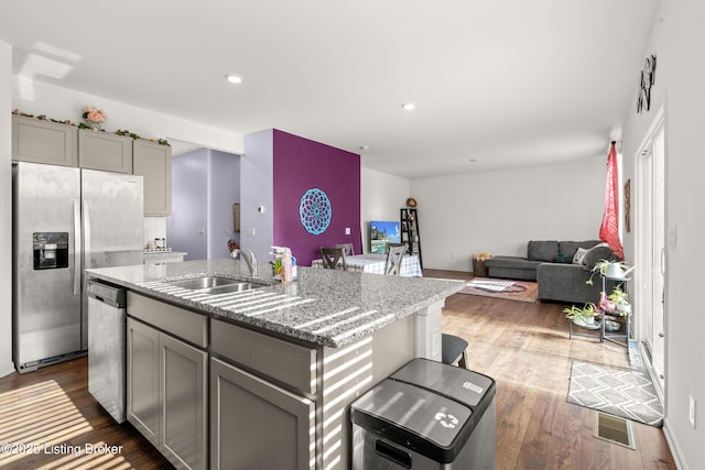 kitchen featuring sink, gray cabinetry, a kitchen island with sink, light stone counters, and stainless steel appliances