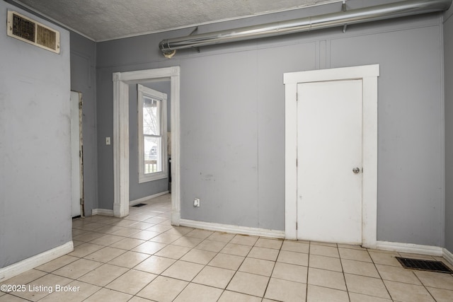 unfurnished room featuring light tile patterned floors and a textured ceiling