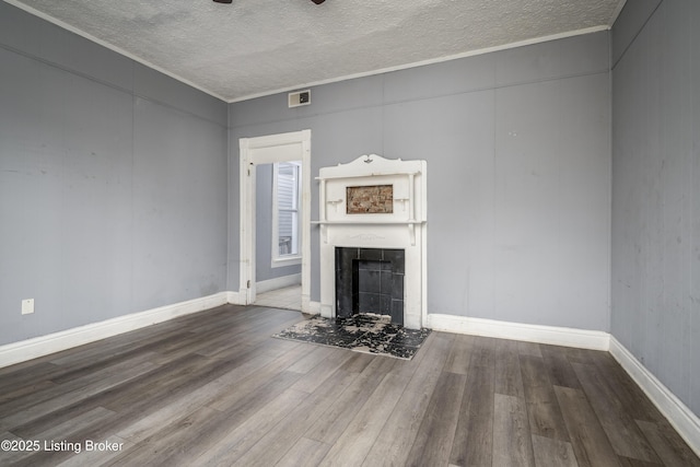 unfurnished living room with a fireplace, wood-type flooring, ornamental molding, and a textured ceiling