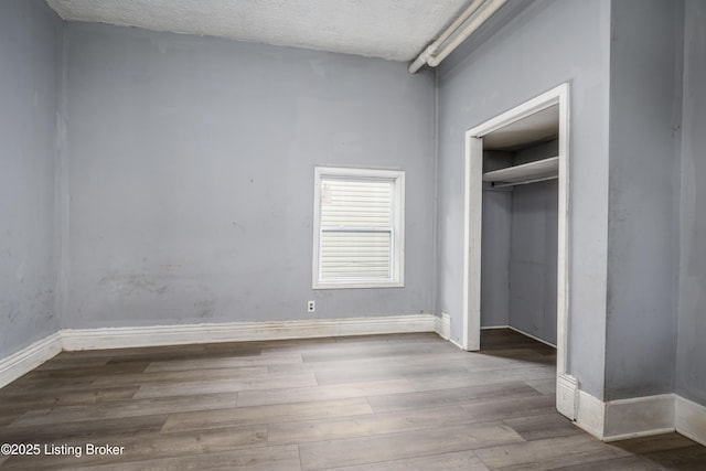 unfurnished bedroom with light hardwood / wood-style floors, a closet, and a textured ceiling