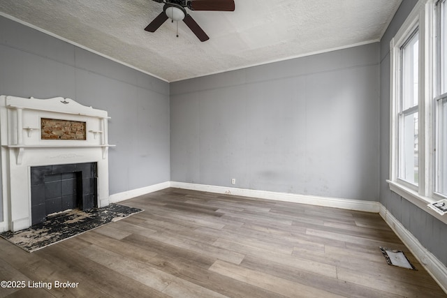 unfurnished living room featuring ornamental molding, hardwood / wood-style floors, a tile fireplace, and a textured ceiling