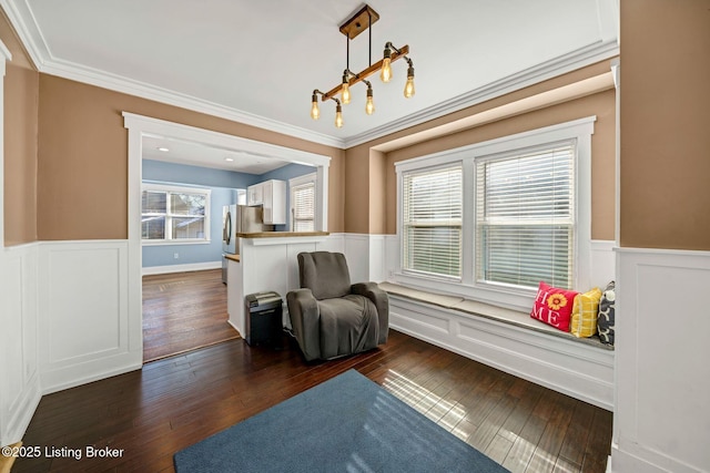 living area featuring crown molding, dark wood-type flooring, and a notable chandelier