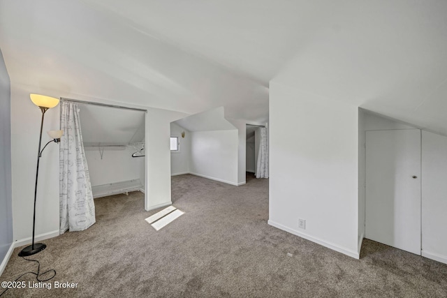 additional living space featuring vaulted ceiling and carpet floors