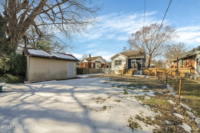 snow covered house featuring a storage shed