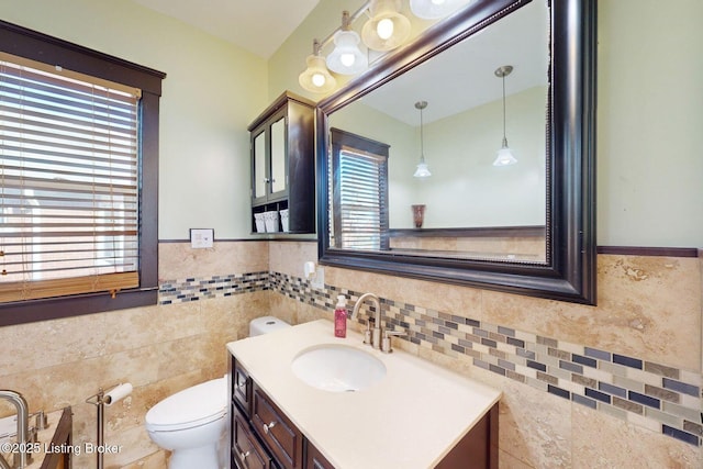 bathroom featuring vanity, toilet, and tile walls