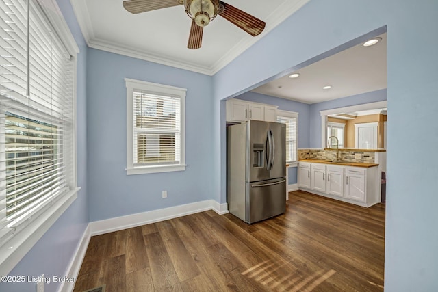 kitchen with stainless steel refrigerator with ice dispenser, dark wood-type flooring, sink, white cabinetry, and crown molding