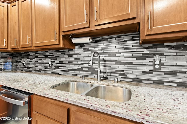 kitchen featuring light stone counters, sink, decorative backsplash, and stainless steel dishwasher