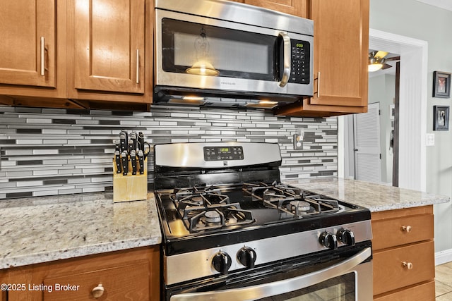 kitchen with stainless steel appliances, light stone countertops, and backsplash