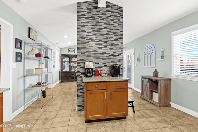 kitchen with light stone counters, lofted ceiling, light tile patterned floors, and backsplash