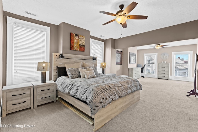 bedroom featuring light carpet, a textured ceiling, and ceiling fan