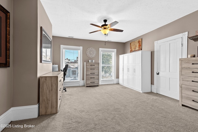 unfurnished bedroom featuring a textured ceiling, light colored carpet, and ceiling fan