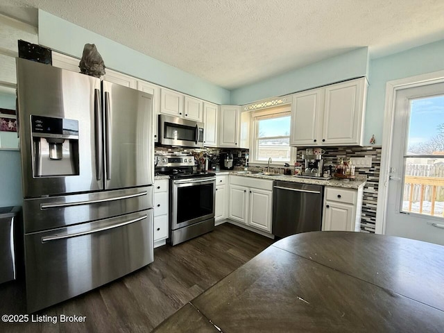 kitchen featuring tasteful backsplash, appliances with stainless steel finishes, white cabinets, and light stone counters